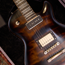 Close-up of a guitar with an EGGLE MACON sunburst finish on a dark background