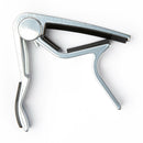 A silver-colored Dunlop Trigger Style Curved Capo made of aircraft quality aluminum, with padded handle and spring-action clamp.